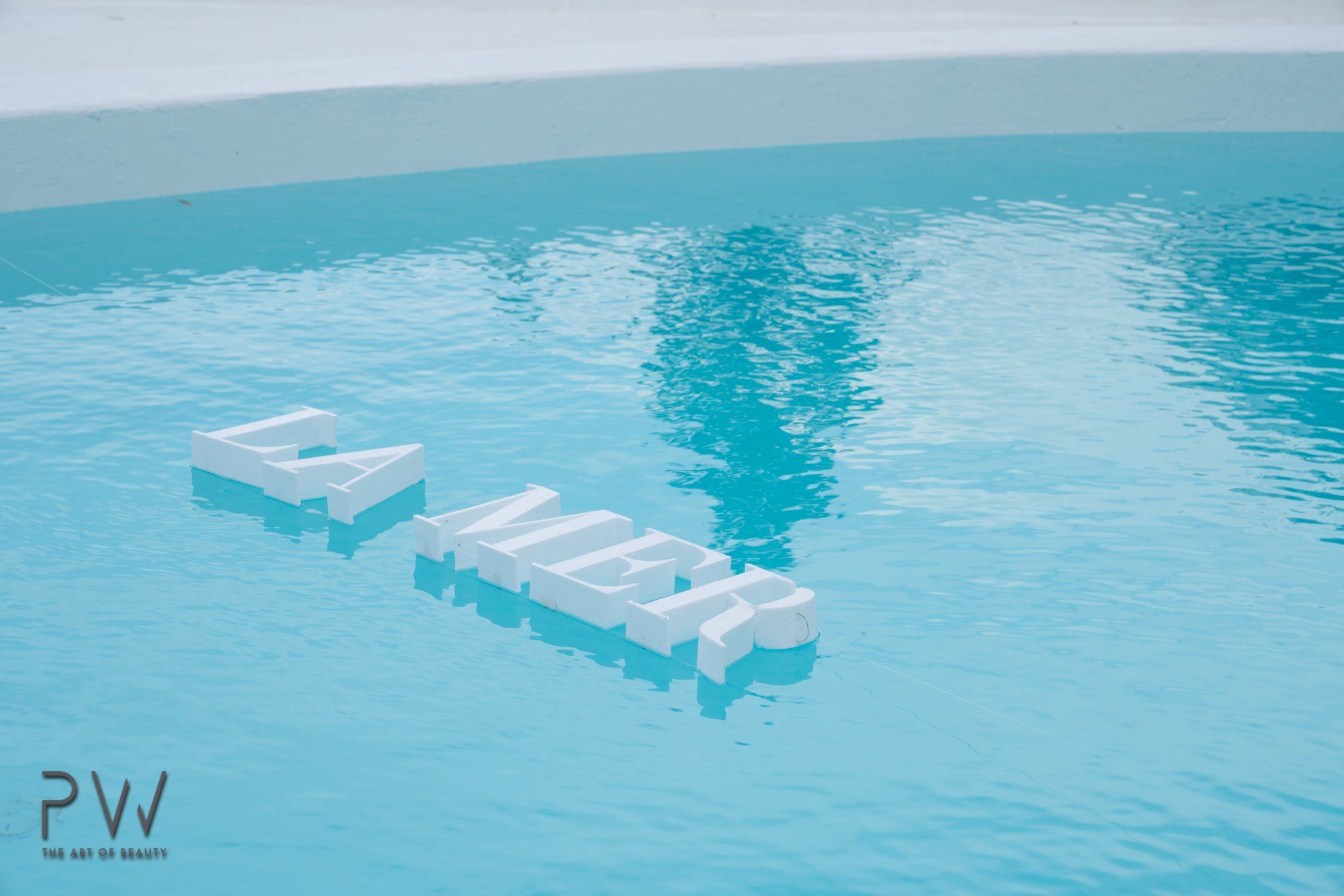 White La Mer lettering floating in a blue swimming pool