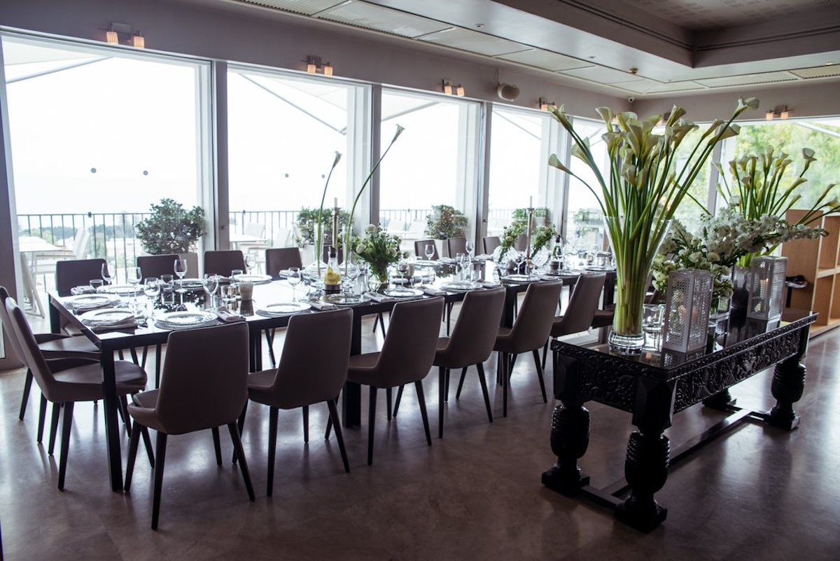 La Mer event dining room with a long table and tall white floral arrangements