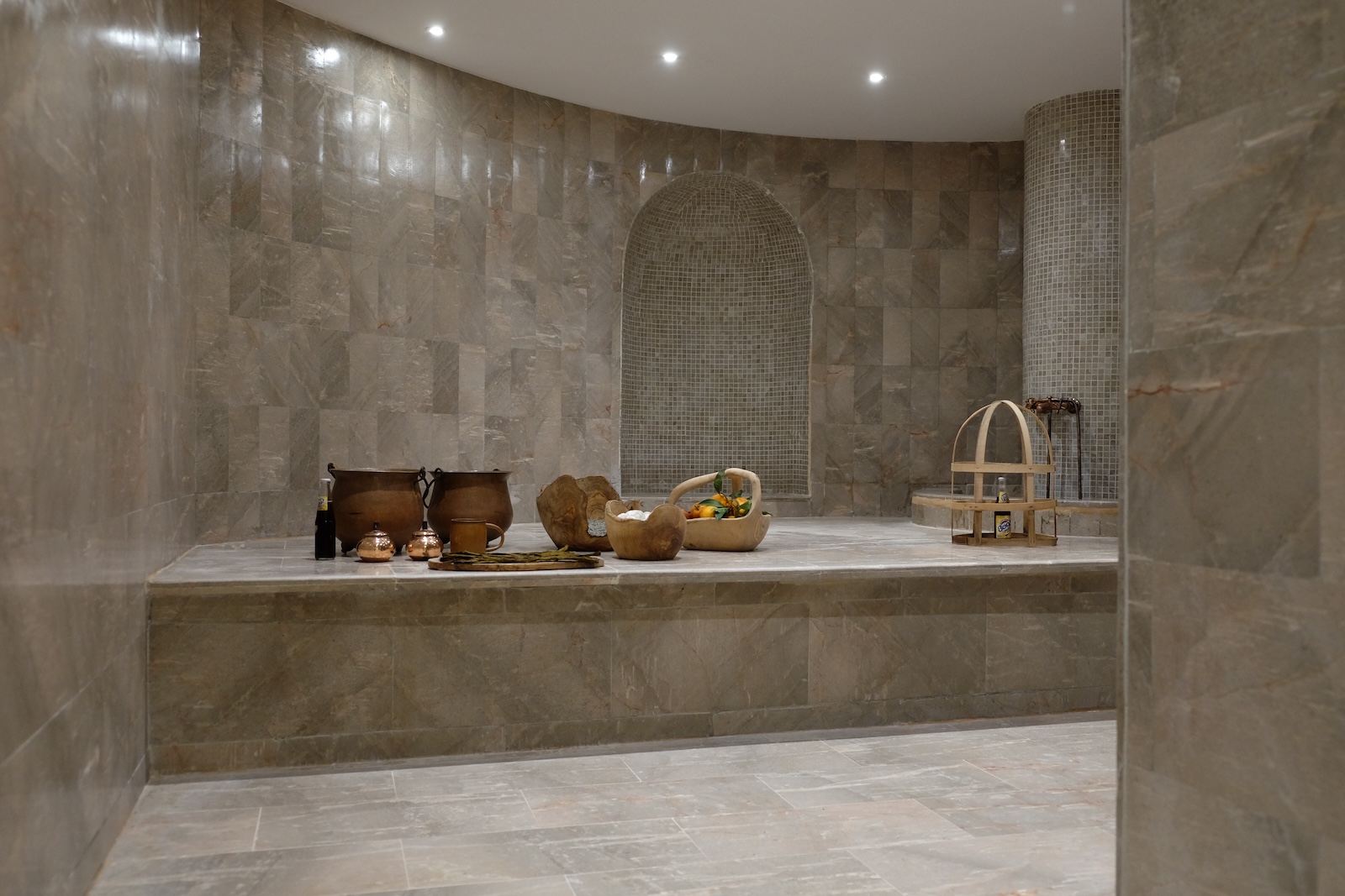 Hammam with marble walls, arched mosaic niche and traditional copper vessels