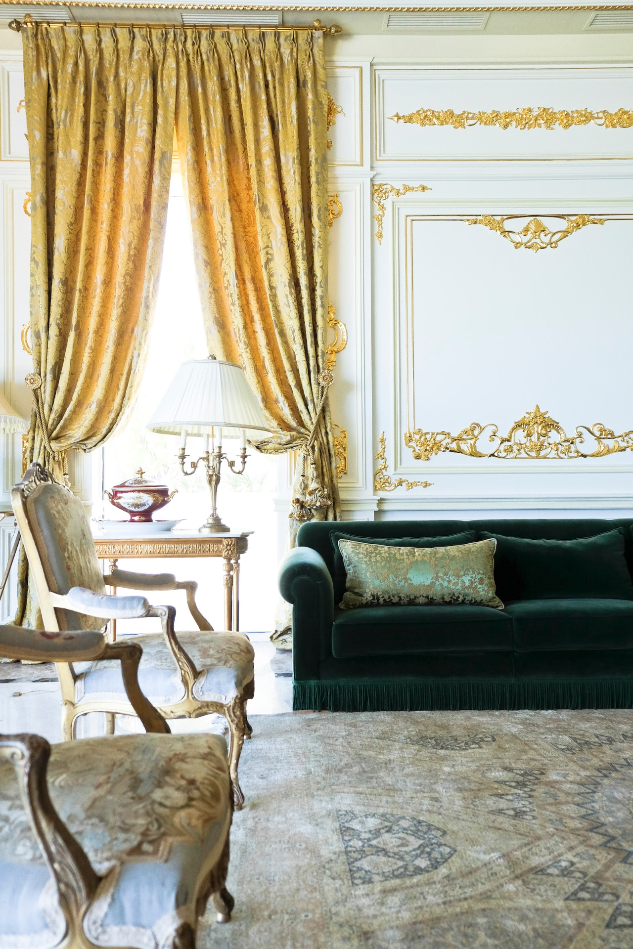 Portrait view of the salon with gold curtains and green velvet sofa