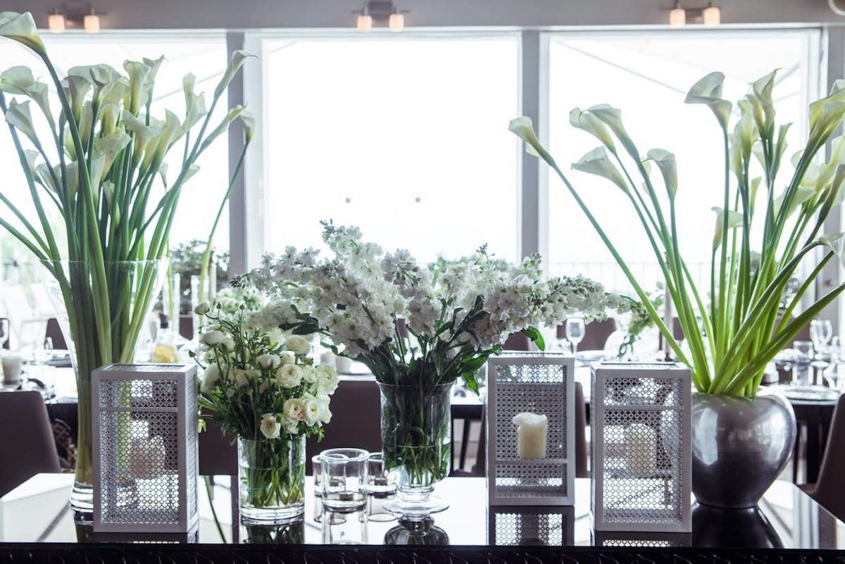 White floral arrangements and lanterns on a reflective table at the La Mer event