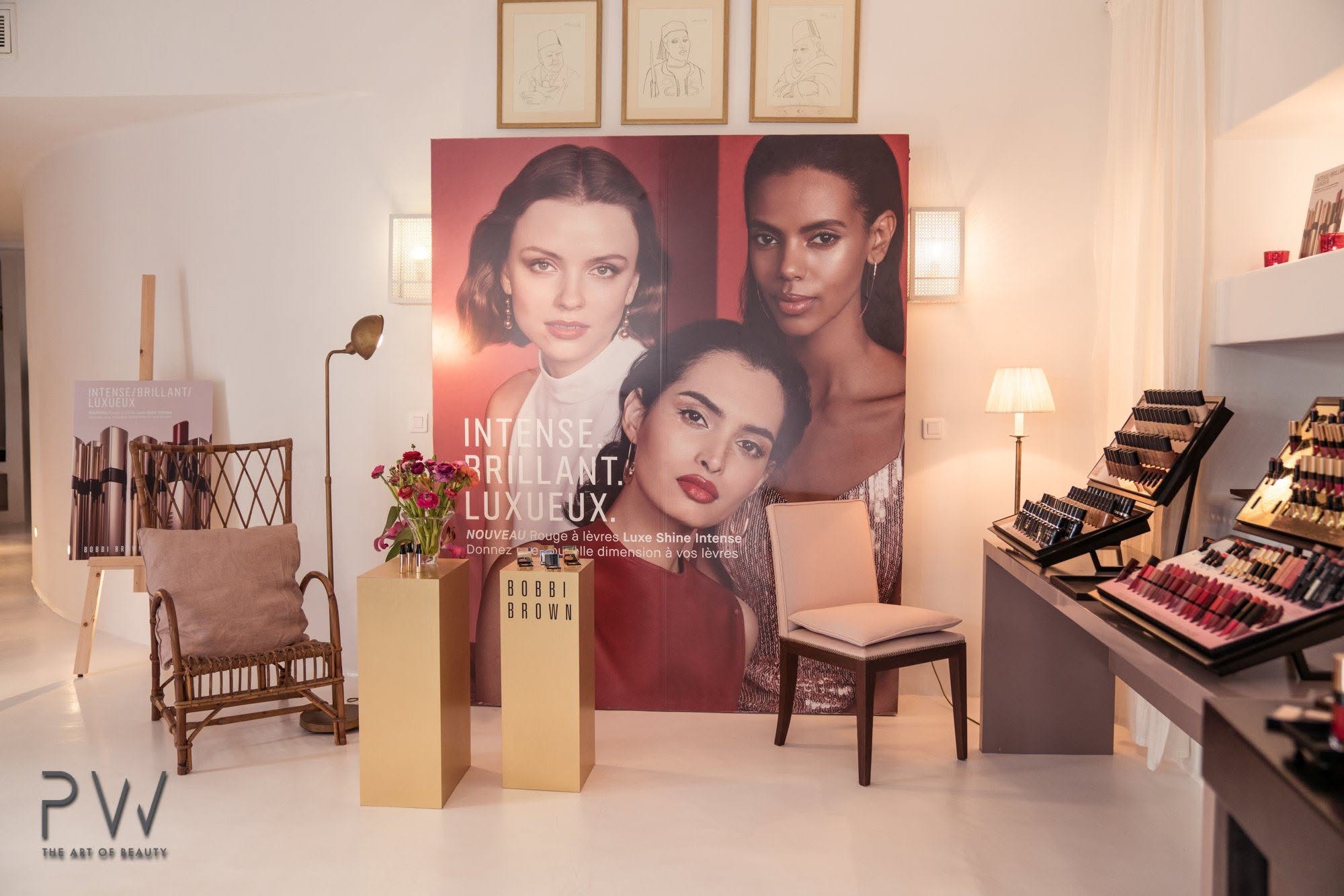 Bobbi Brown launch space with campaign portrait, product displays and rattan armchair