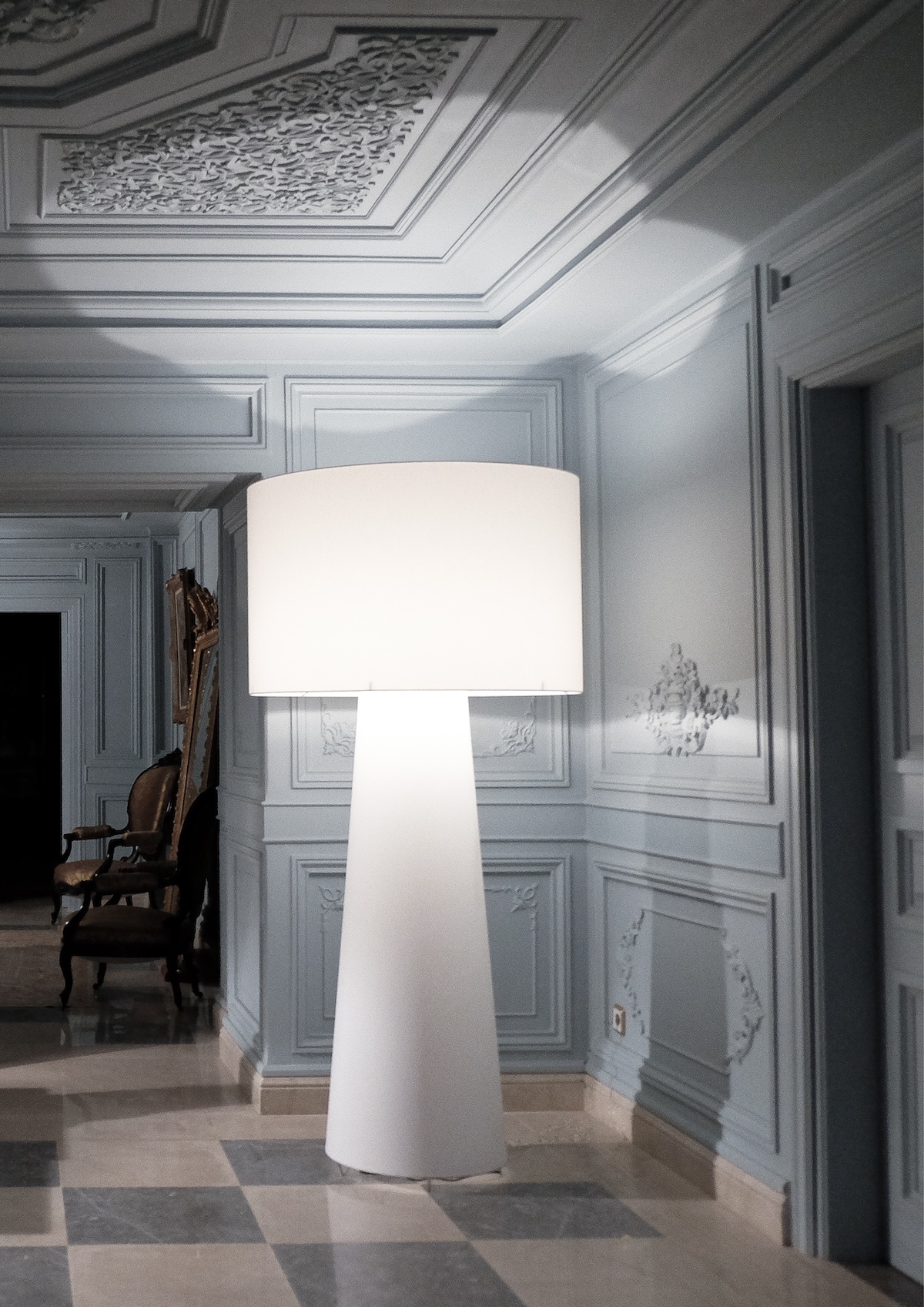 Large white floor lamp in panelled hall with chequered marble floor