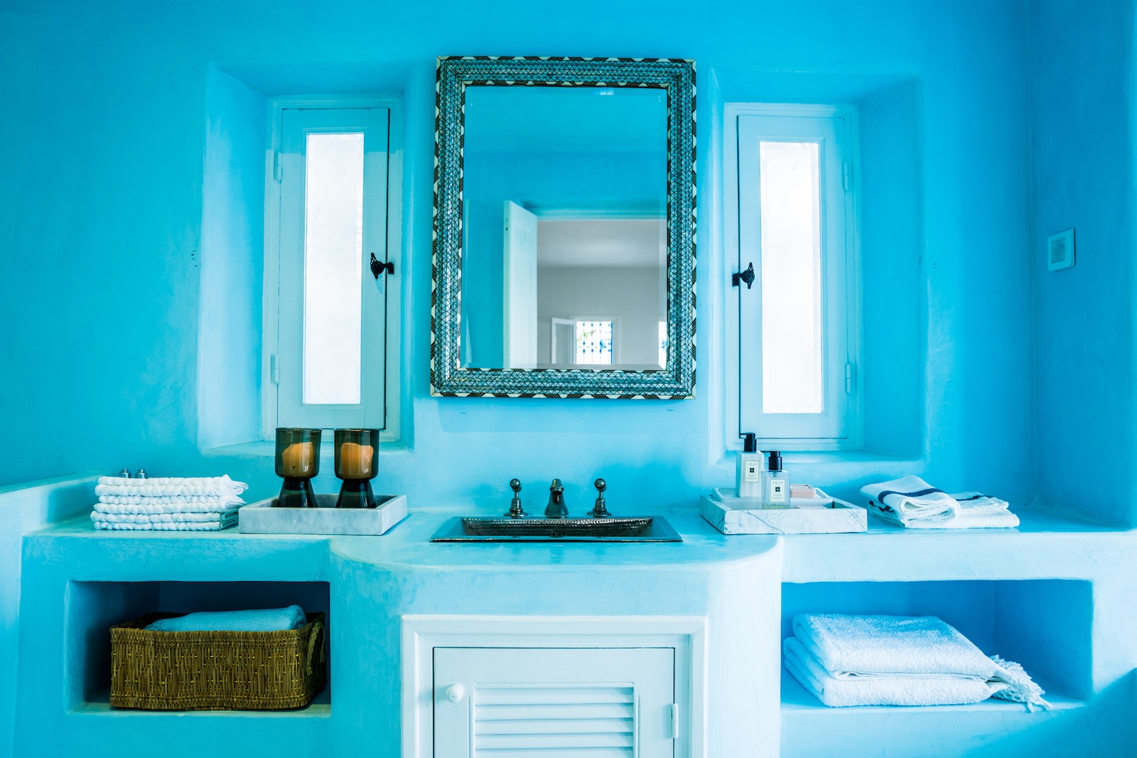 Blue bathroom vanity with a metal sink and a framed mirror
