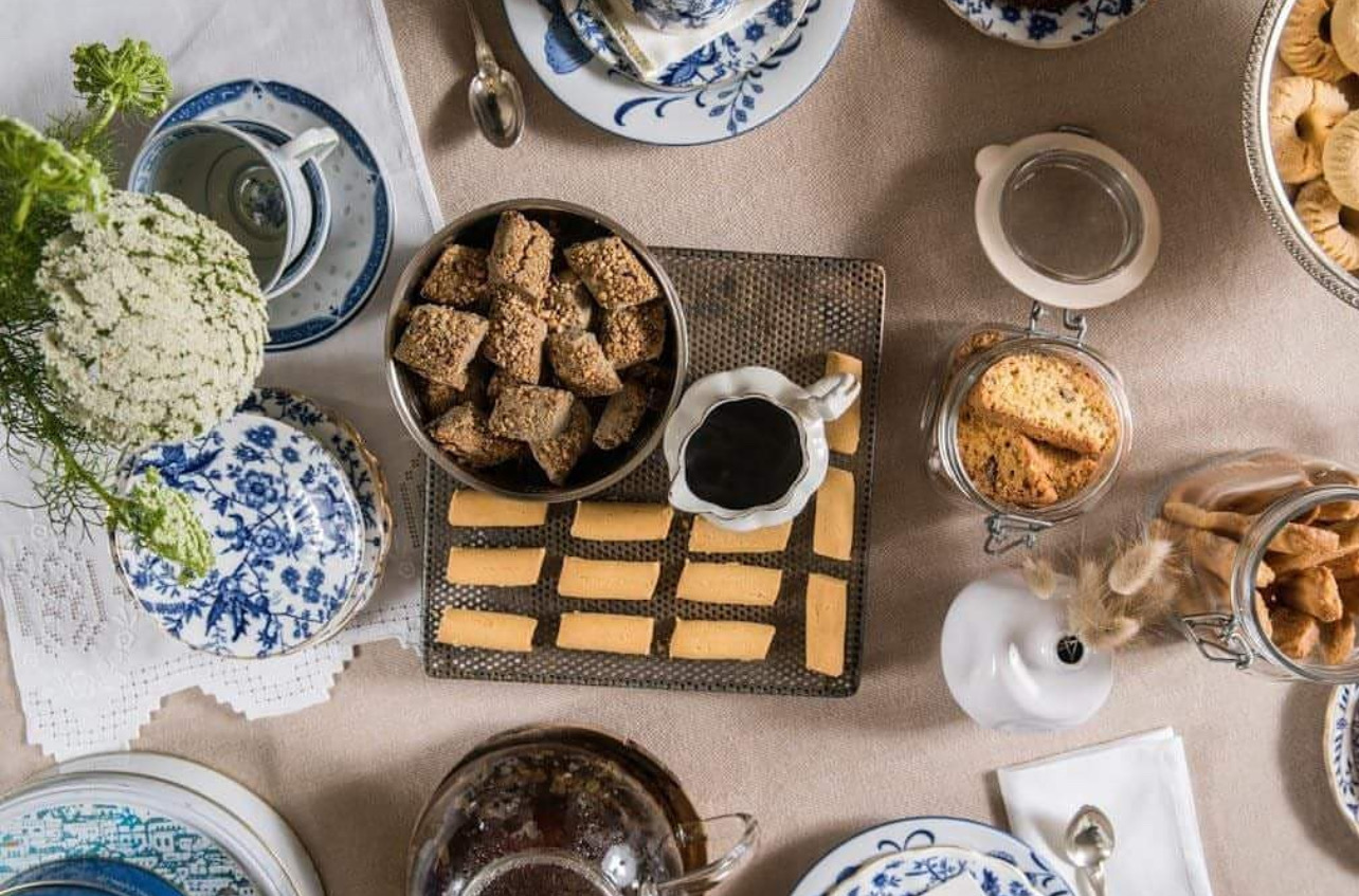 Overhead table with blue-and-white porcelain cups, jars of biscuits and a tray of almond sweets