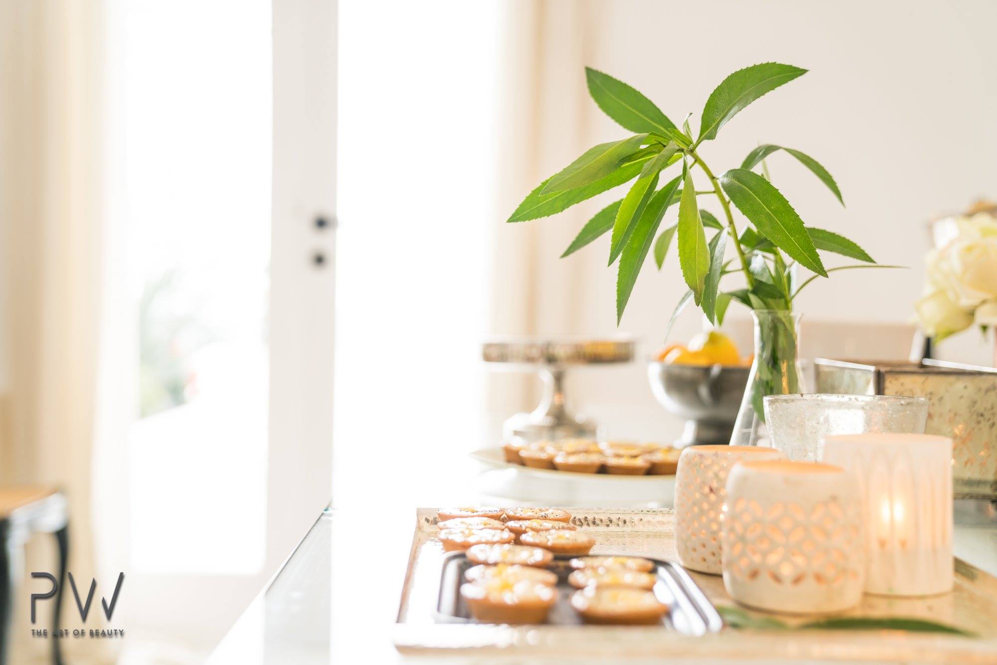 Pastries, candles and greenery arranged on a bright event table
