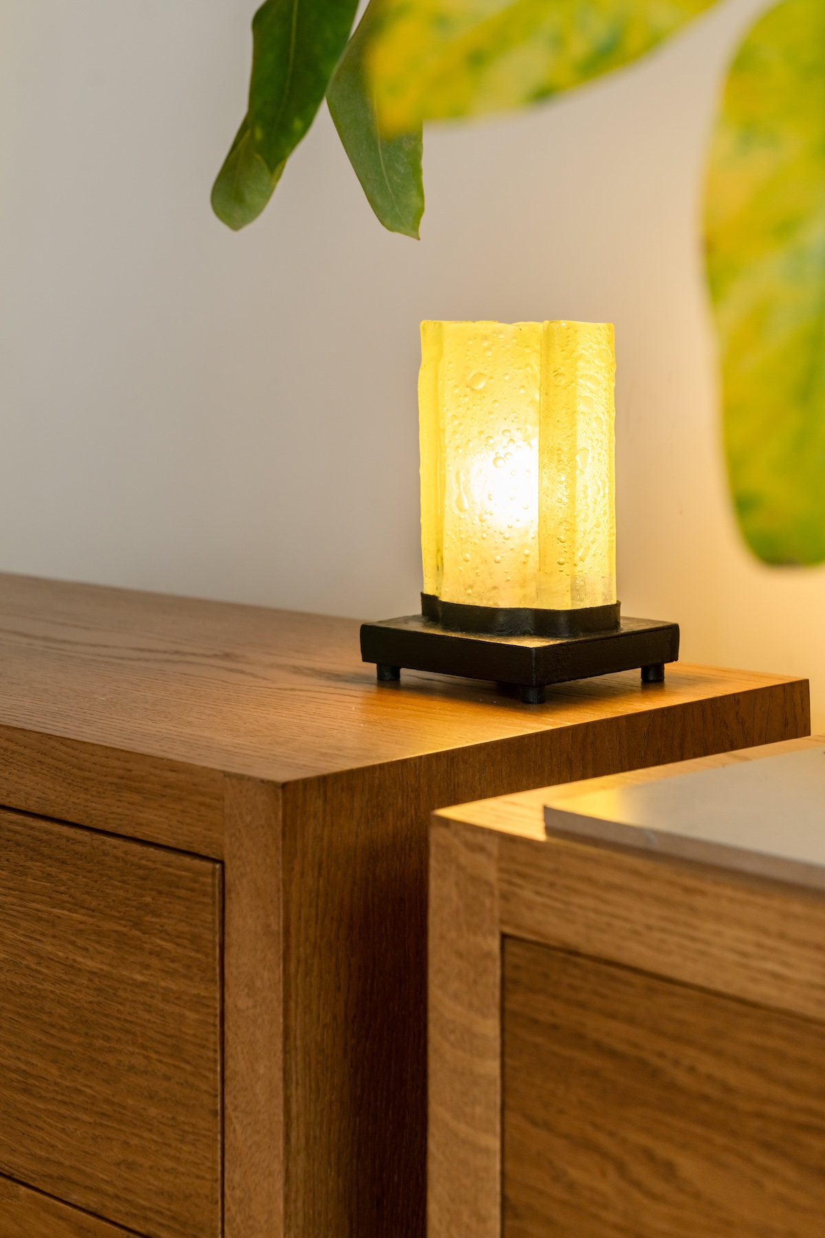 Glowing yellow glass lamp on a wooden cabinet