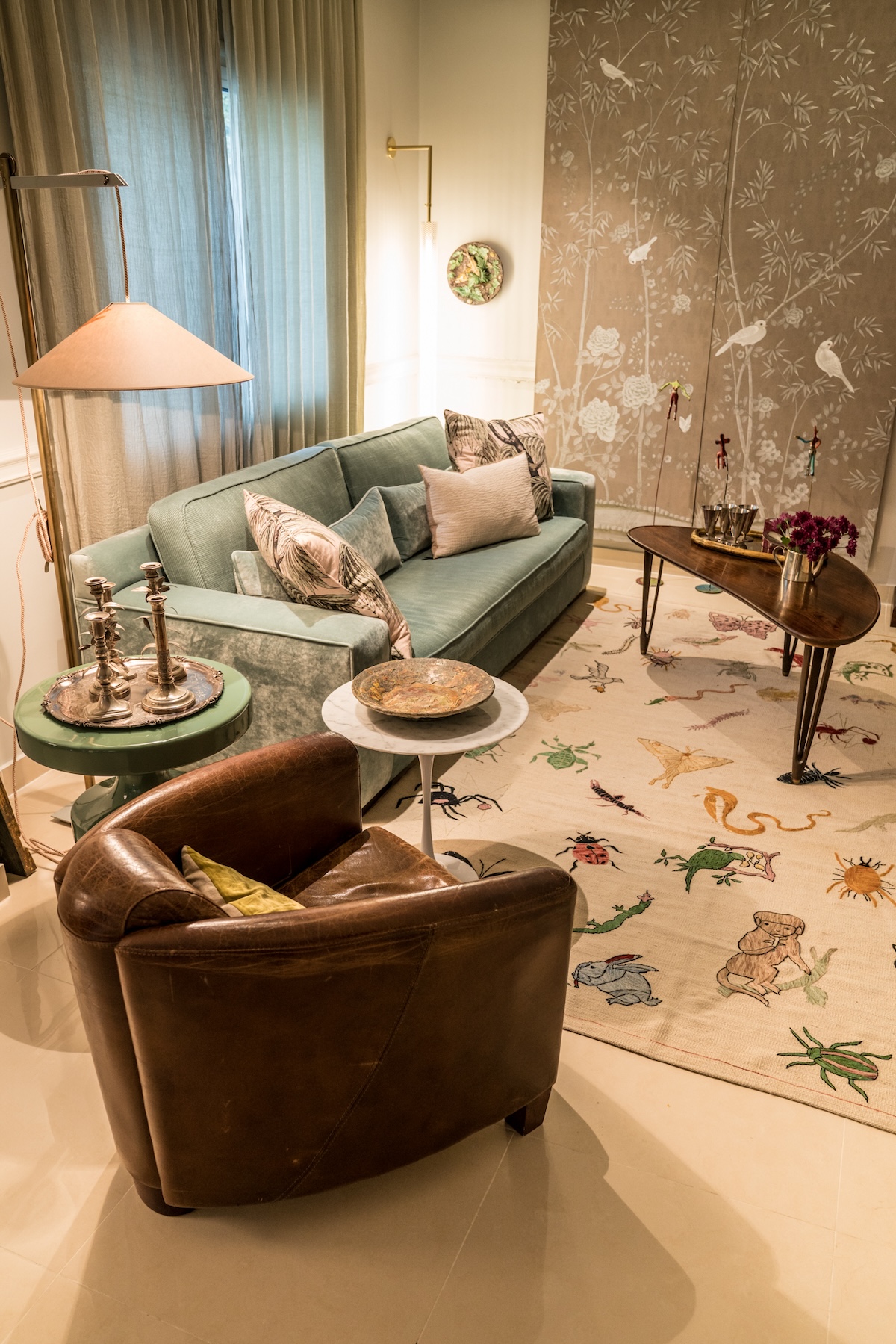 Living room with green sofa, leather armchair and illustrated rug