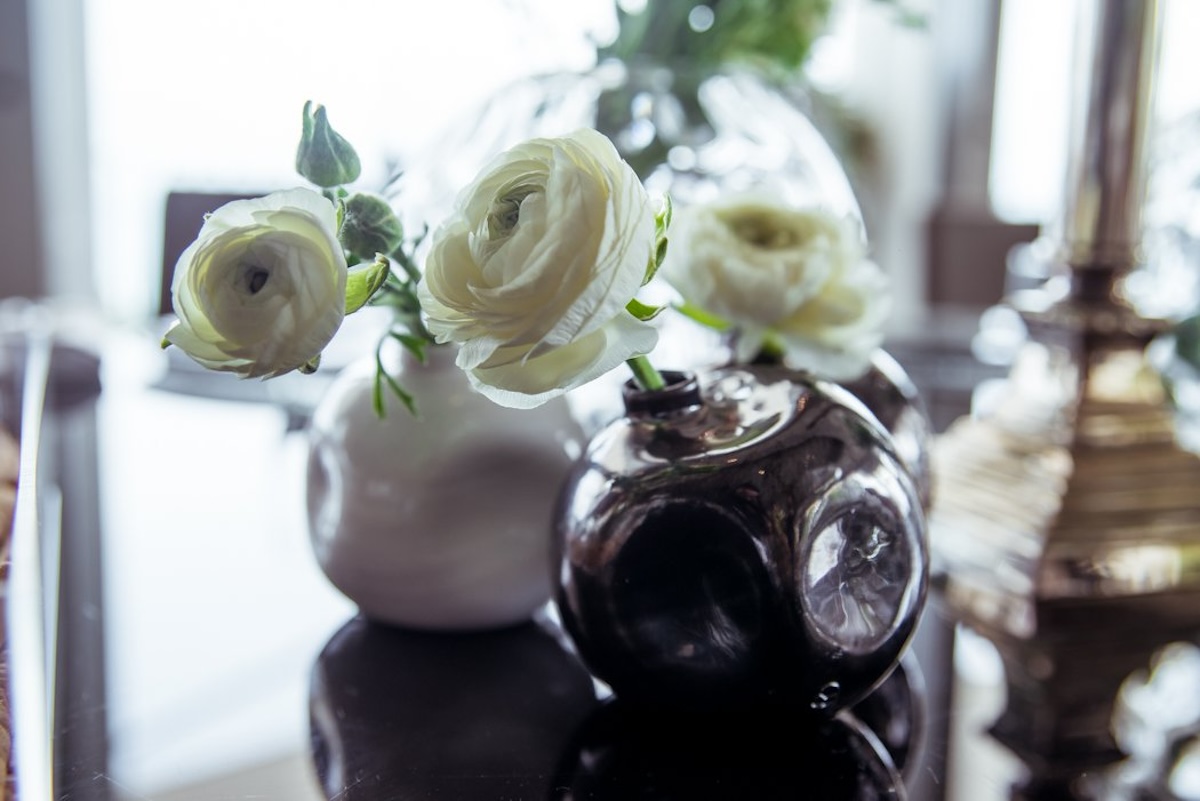 White flowers arranged in reflective vases on a dining table