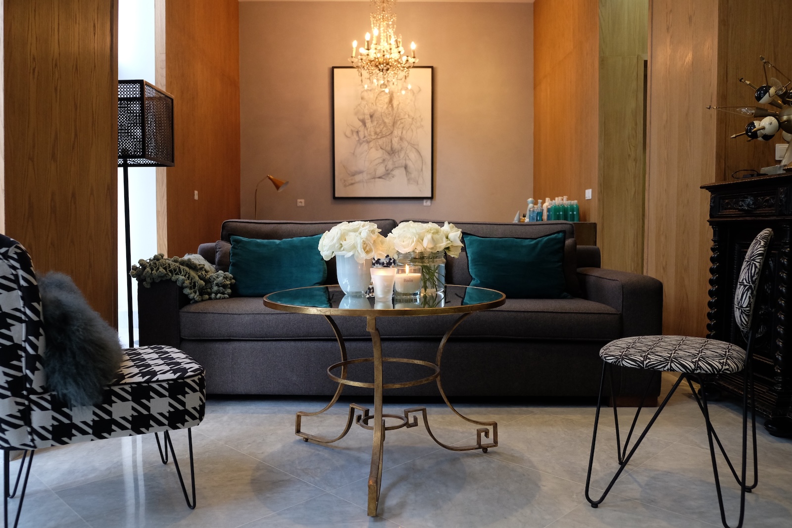 Relaxation lounge with grey sofa, brass coffee table and crystal chandelier