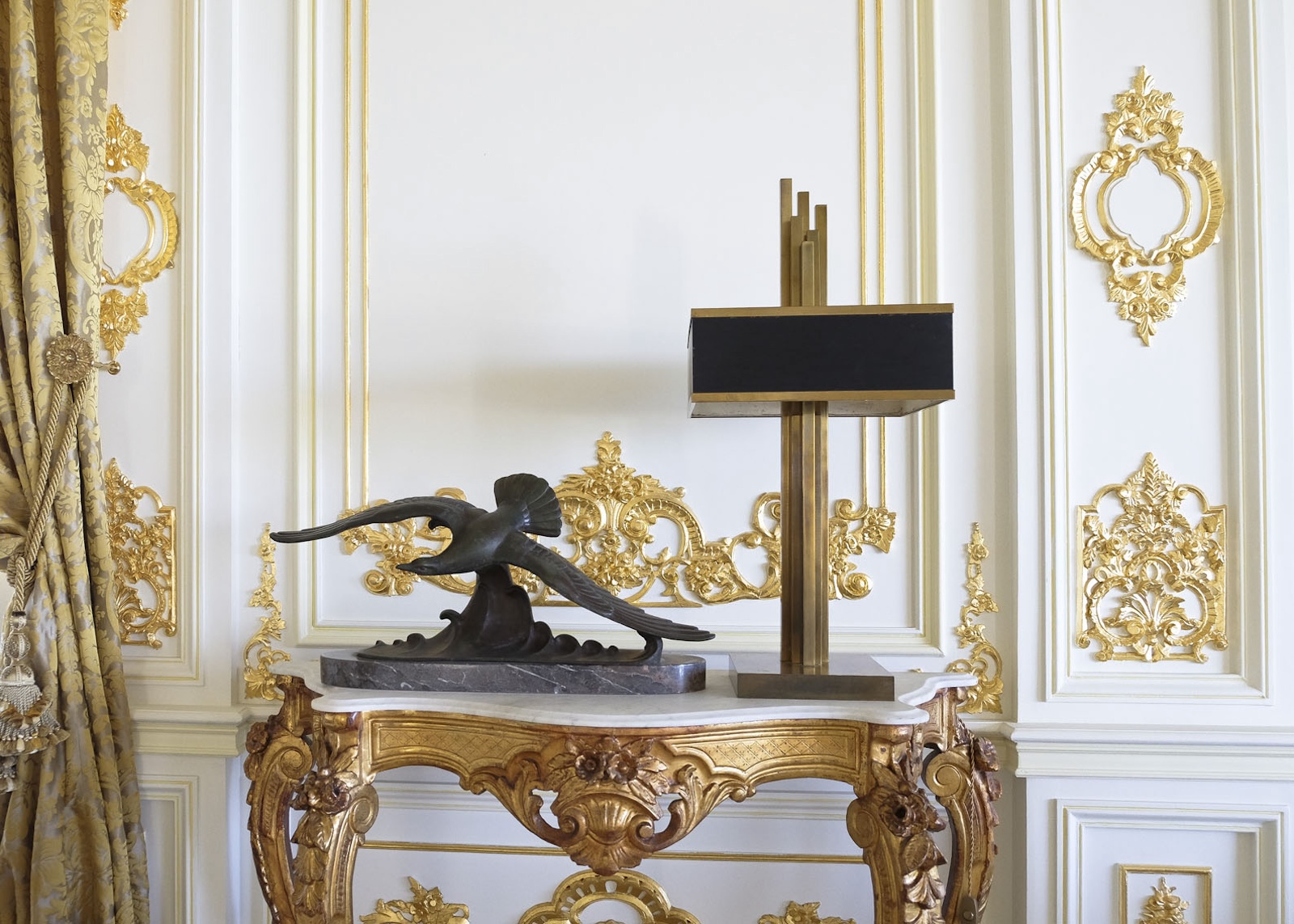 Sculpture and table lamp on an ornate gilded console