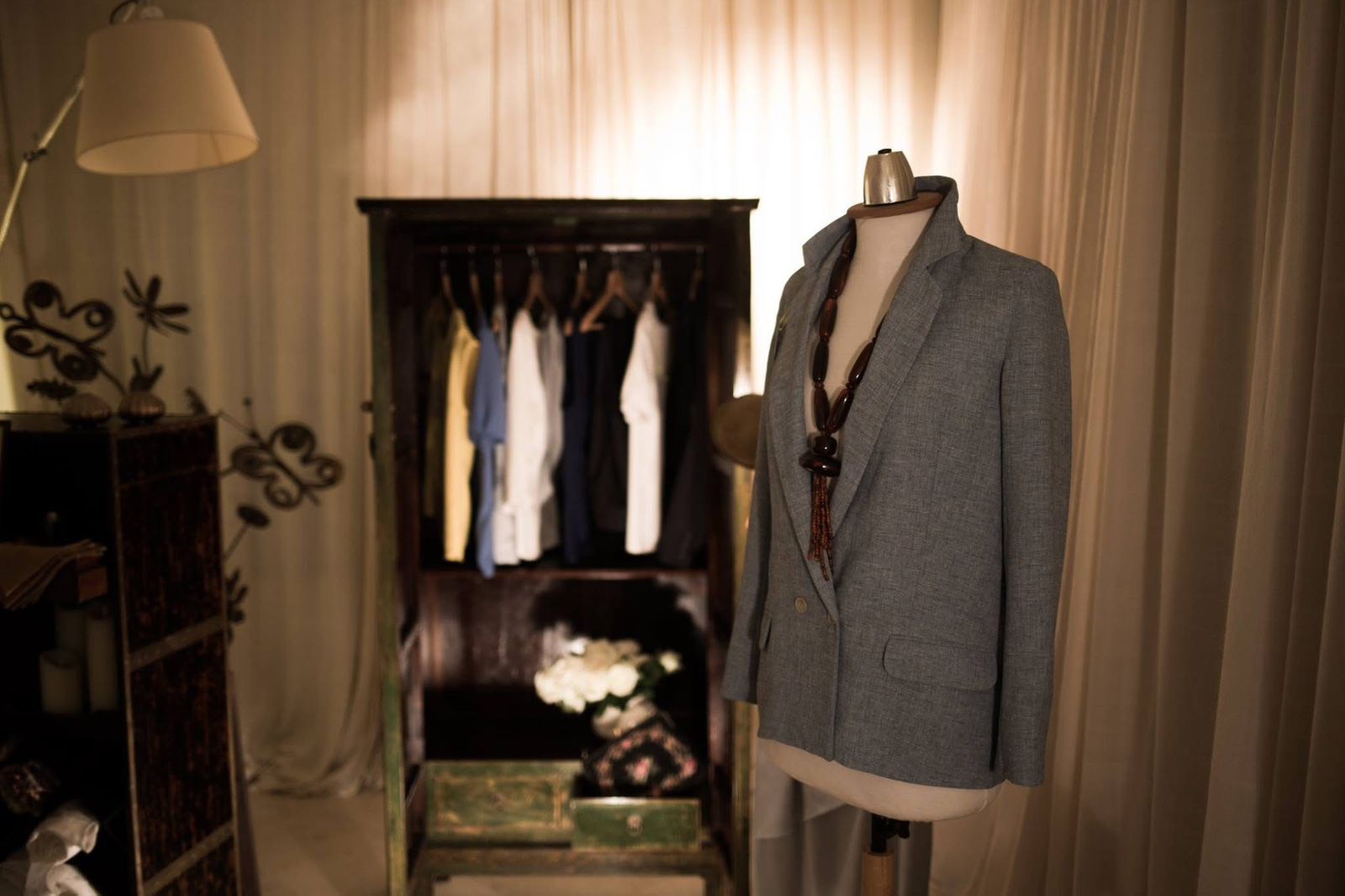 Tailored grey jacket displayed before a dark wooden wardrobe