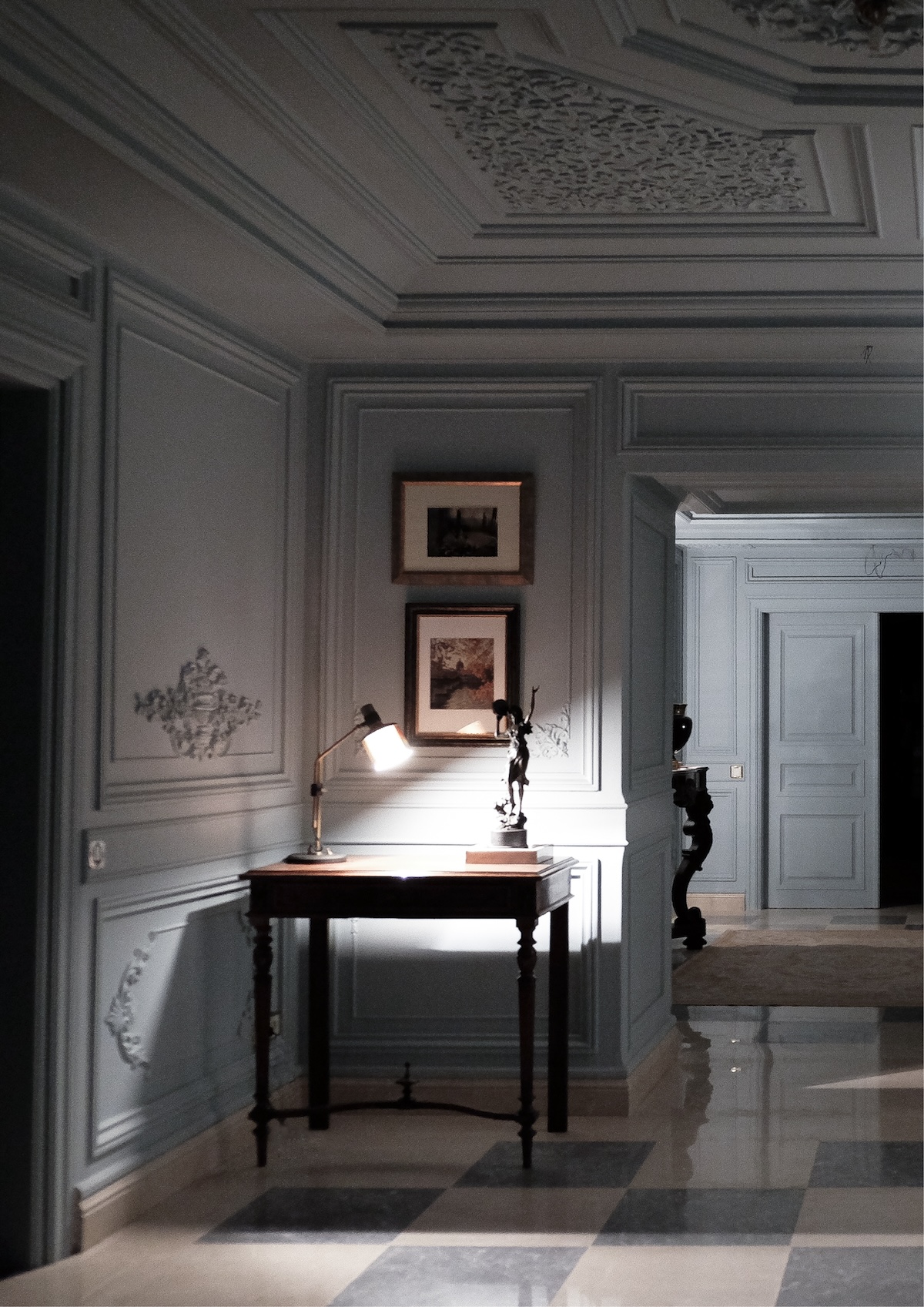 Panelled hall with wooden console table, lit desk lamp and sculpture