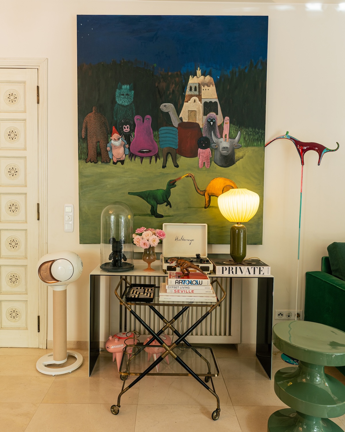 Console with lamp and books beneath a large painting