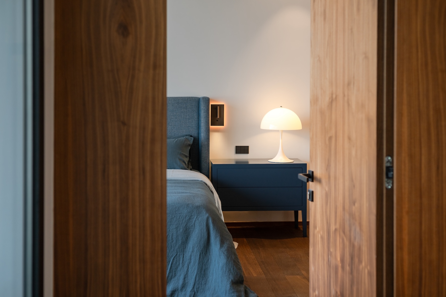 Bedroom seen through walnut doors