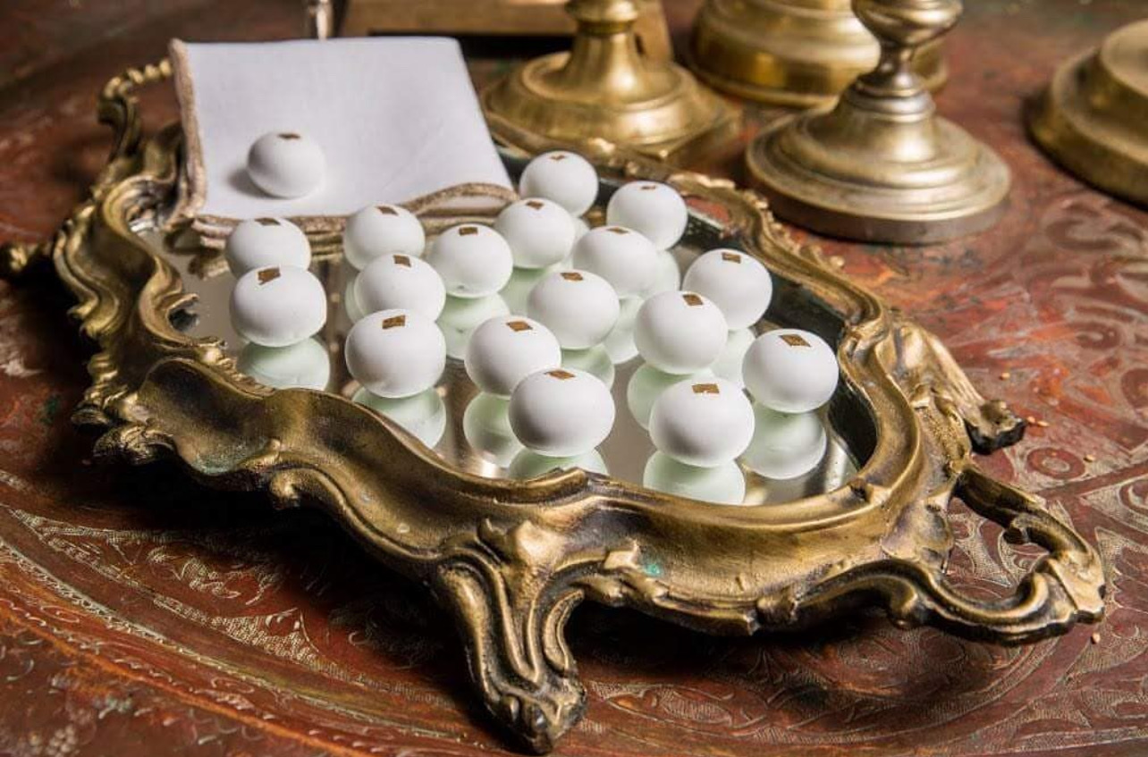 White sugared sweets with gold leaf arranged on an ornate gilt mirror tray