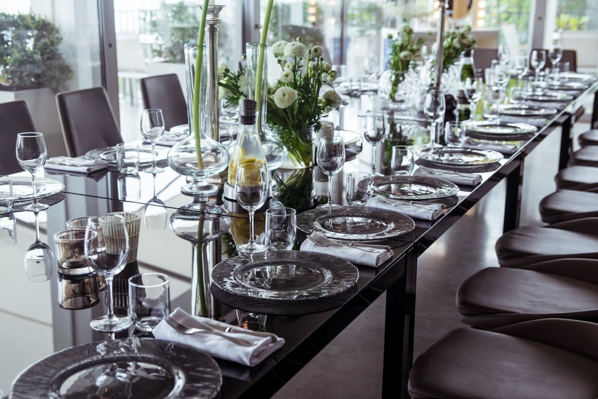 Long dining table set with glassware and white floral arrangements
