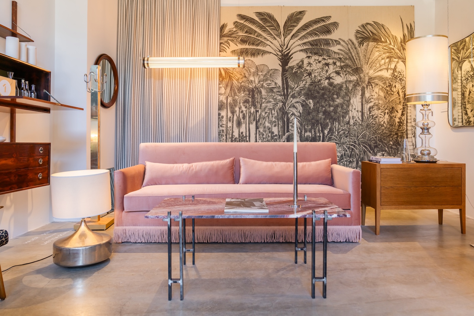 Living area with pink velvet sofa, marble coffee table and palm-tree wall panels