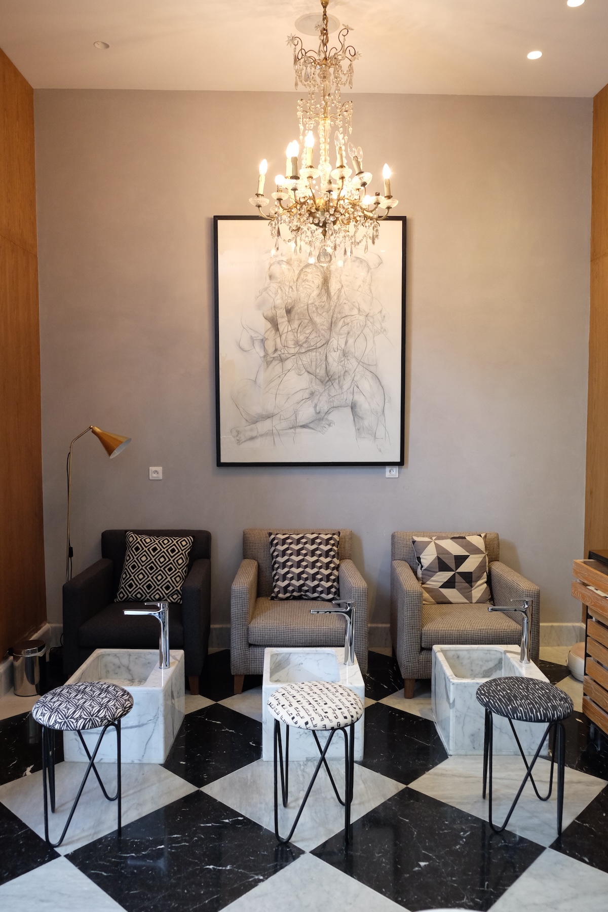 Pedicure area with armchairs, marble basins and large drawing under a chandelier