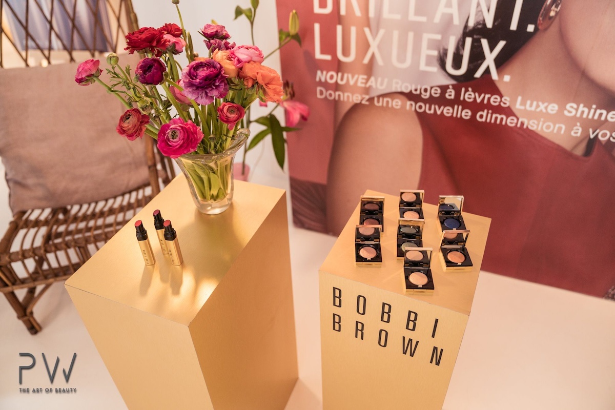 Bobbi Brown gold pedestals with lipsticks, eyeshadows and fresh flowers